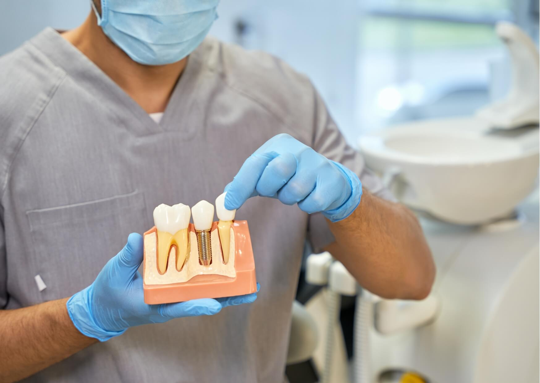 Dentist using a dental implant model to explain treatment and answer common questions about MRI safety with dental implants.