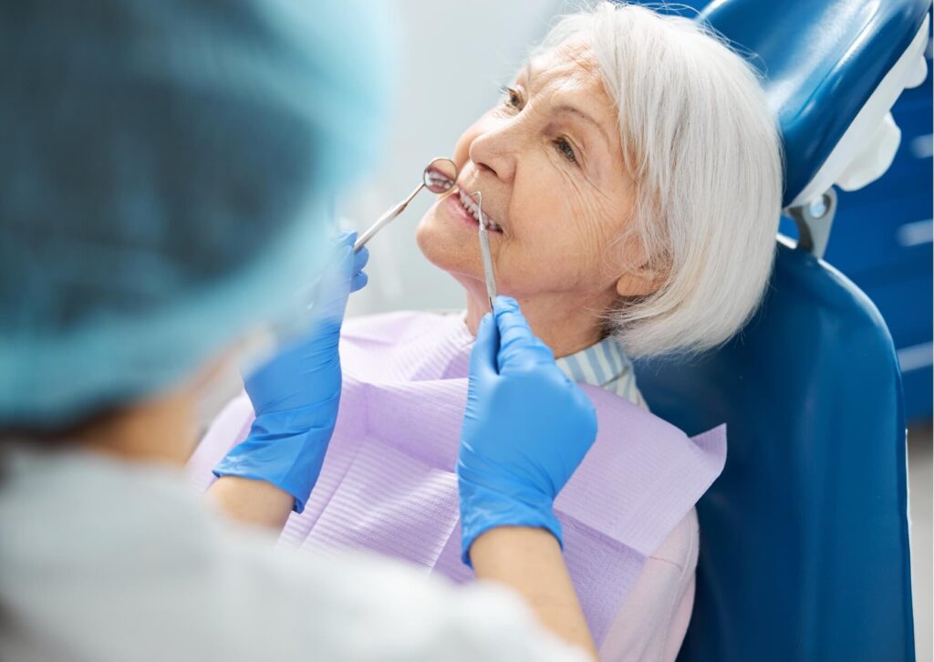 Dentist examining an older adult during a dental implant consultation to determine whether it is too late to get dental implants.