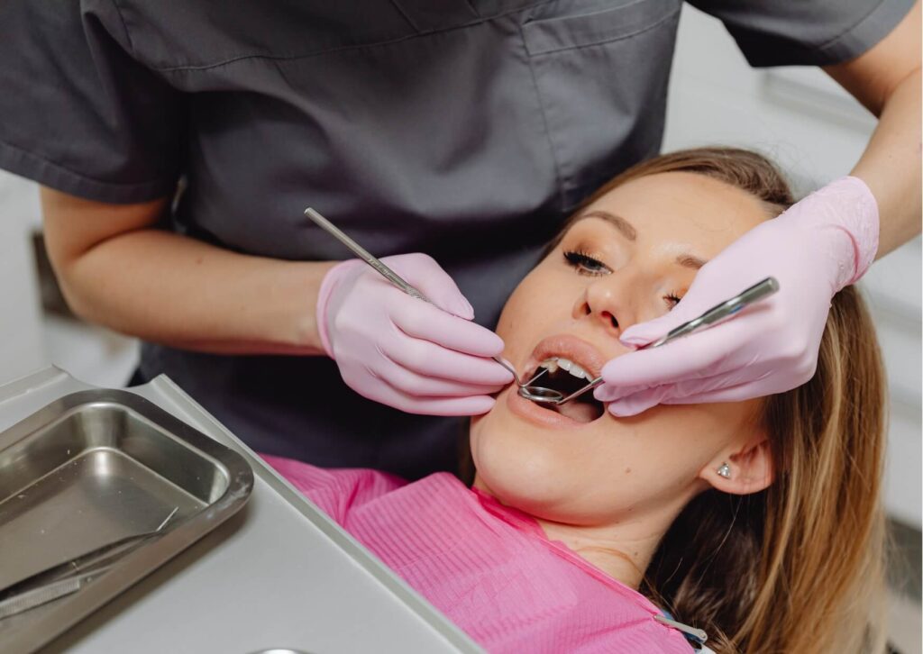 Dentist examining a patient's teeth during an oral exam to diagnose a rotten tooth, severe decay, or dental infection.