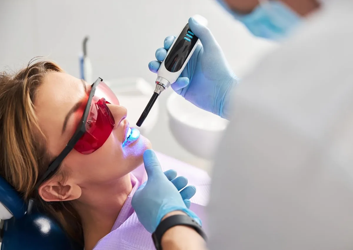 Dentist applying a protective dental sealant to a patient&rsquo;s teeth to help prevent cavities.