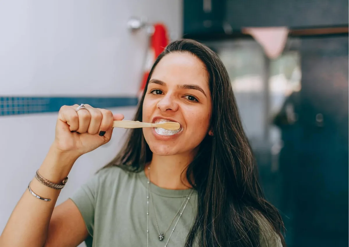 Woman brushing her teeth to help protect against cavities alongside the use of dental sealants.
