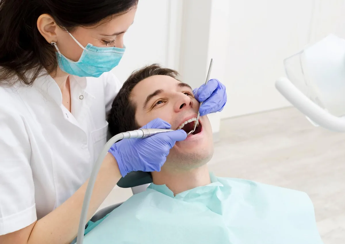 Dental professional removing plaque from a patient’s teeth during a professional dental cleaning.